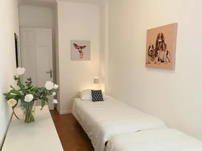 a white room with two beds and a vase of flowers at Le Maréchal in Nice