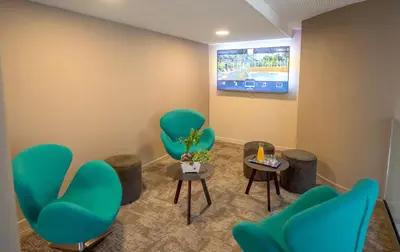 a waiting room with green chairs and a tv at Hotel Lou Castelet in Carros