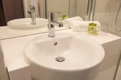 a white bathroom with a sink and a mirror at Hotel Lou Castelet in Carros
