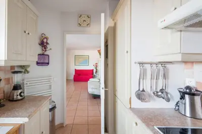 a kitchen with white cabinets and a red couch at Appartement Lanterne Welkeys in Nice