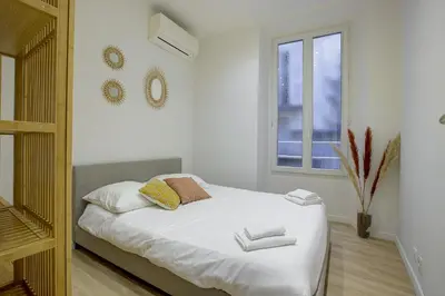 a bedroom with a bed with white sheets and a window at Maison Bianchi - Raspail in Nice