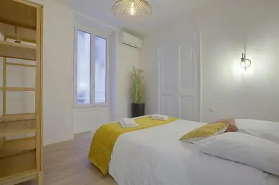 a white bedroom with a large bed and a window at Maison Bianchi - Raspail in Nice