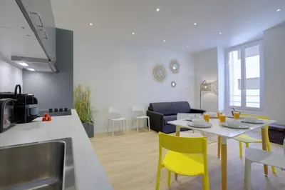 a kitchen and living room with a table and yellow chairs at Maison Bianchi - Raspail in Nice
