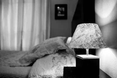 a lamp on a night stand next to a bed at Hotel Victor Hugo Nice in Nice