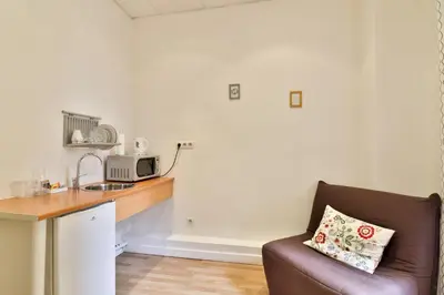 a living room with a couch and a kitchen at Hotel Victor Hugo Nice in Nice