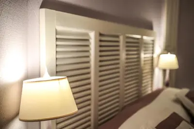 a bedroom with a headboard and a lamp next to a bed at Hotel Victor Hugo Nice in Nice