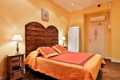 a bedroom with a large bed with a wooden headboard at Hotel Victor Hugo Nice in Nice