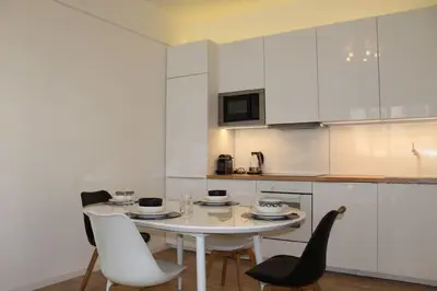a white kitchen with a white table and chairs at Nice Plein Centre, Calme et Proche de la mer in Nice