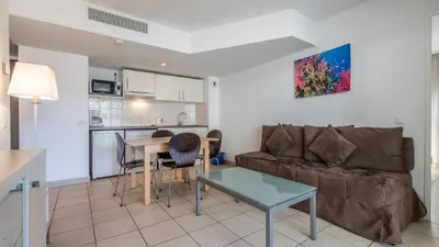 a living room with a couch and a table at Vacancéole - Résidence Le Crystal in Cagnes-sur-Mer