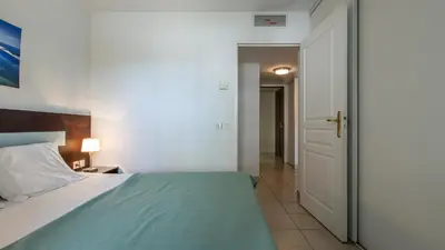 a bedroom with a bed and a door to a hallway at Vacancéole - Résidence Le Crystal in Cagnes-sur-Mer