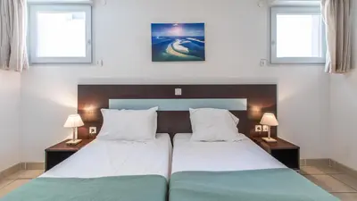 a bedroom with a large bed with two tables and two windows at Vacancéole - Résidence Le Crystal in Cagnes-sur-Mer