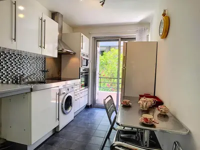 a kitchen with a table and a sink and a refrigerator at Nestor&Jeeves - DEBUSSY TERRASSE - Central - By shopping area in Nice