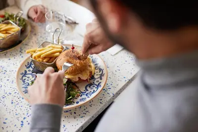 a person eating a sandwich and french fries on a table at Hotel Restaurant Isidore by Soniho in Nice
