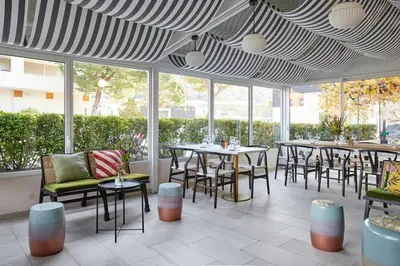 a restaurant with tables and chairs and windows at Hotel Restaurant Isidore by Soniho in Nice