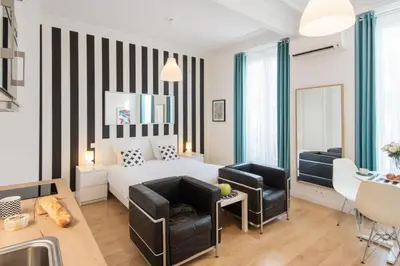 a bedroom with a white bed and two chairs at Le Studio Graphite Welkeys in Nice