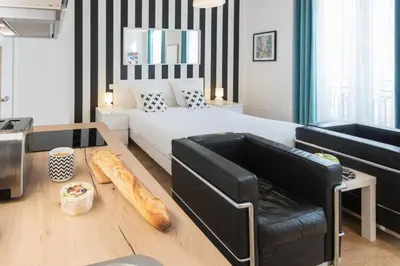 a bedroom with a bed and a couch and a table at Le Studio Graphite Welkeys in Nice