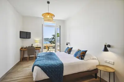 a bedroom with a bed and a desk in a room at Hotel De La Darse in Villefranche-sur-Mer