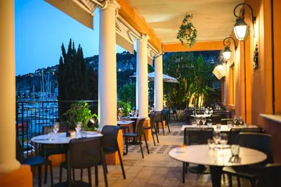 a restaurant with tables and chairs on a patio at Hotel De La Darse in Villefranche-sur-Mer