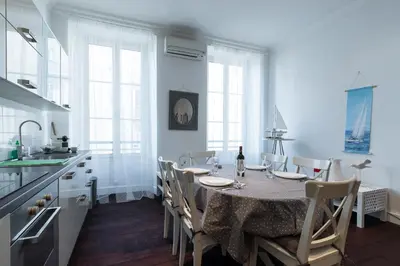 a dining room with a table with chairs and a kitchen at Prestige Apartment, near the beaches in Nice