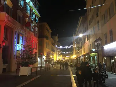 a city street at night with people walking down the street at Prestige Apartment, near the beaches in Nice