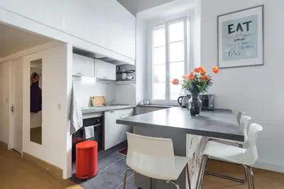 a kitchen with a table and white chairs and a counter at Nicelidays - Le Suede - Carré d'or - 2min from beaches in Nice