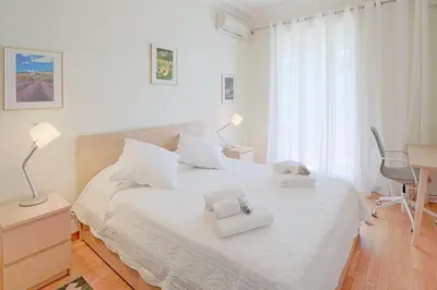 a white bedroom with a bed with two towels on it at le capitole in Nice