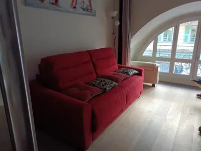 a red couch in a living room with a window at Sam Le Lezard Sarl in Nice