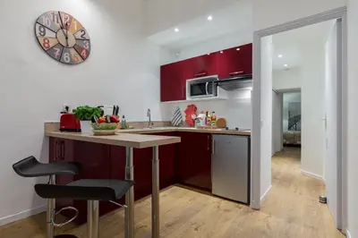 a kitchen with red cabinets and a clock on the wall at Large one bedroom flat in the Old Town in Nice