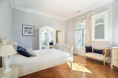 a white bedroom with a bed and a chair at Semiramis in Villefranche-sur-Mer