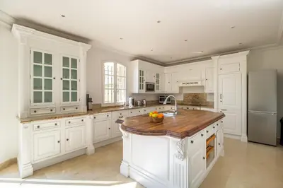 a kitchen with white cabinets and a wooden counter top at Semiramis in Villefranche-sur-Mer
