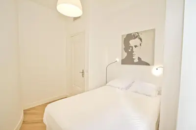 a white bedroom with a bed and two lights at PROMENADE HOLIDAY - SOLEMAR PROMENADE in Nice
