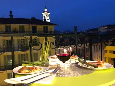 a table with two plates of pizza and a glass of wine at Chez Kari-top location in charming old town in Nice
