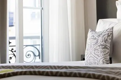 a bed with a pillow next to a window at Hotel 66 Nice in Nice