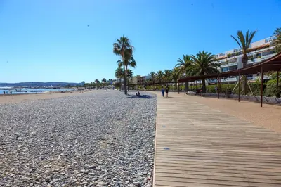a boardwalk on a beach with palm trees and buildings at Sea view luxury apartment in Saint-Laurent-du-Var