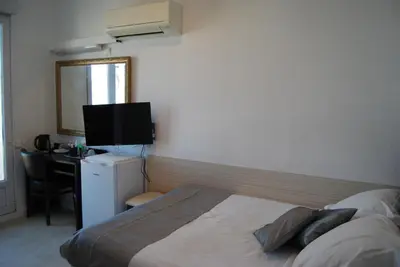 a bedroom with a bed and a desk and a television at Hôtel Azur in Nice