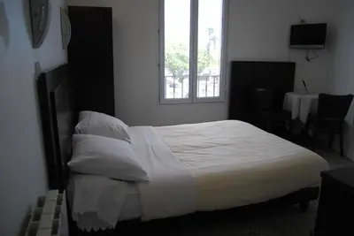 a bedroom with a white bed with a window at Hôtel Azur in Nice