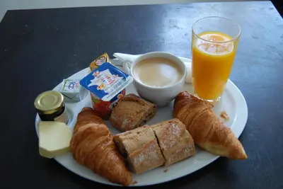 a plate of food with bread and coffee and a glass of orange juice at Hôtel Azur in Nice