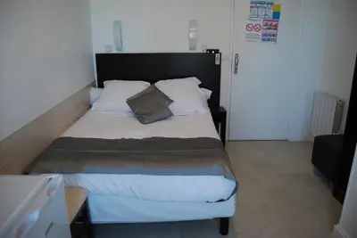 a bedroom with a large bed with a black headboard at Hôtel Azur in Nice