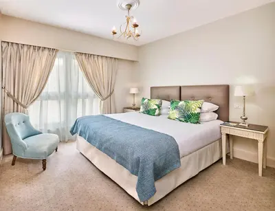 a bedroom with a large bed and a blue chair at La Résidence de La Réserve in Beaulieu-sur-Mer