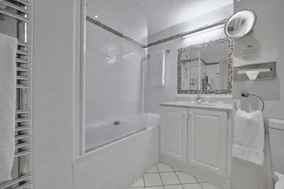 a white bathroom with a tub and a sink at La Résidence de La Réserve in Beaulieu-sur-Mer