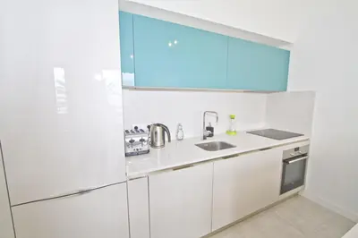 a white kitchen with blue cabinets and a sink at PROMENADE HOLIDAY - AZUR PROMENADE in Nice