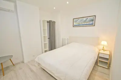 a white bedroom with a bed and a table at PROMENADE HOLIDAY - AZUR PROMENADE in Nice