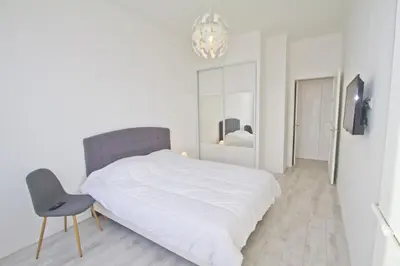 a white bedroom with a bed and a chair at PROMENADE HOLIDAY - AZUR PROMENADE in Nice