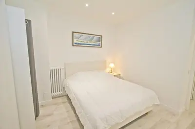 a white bedroom with a bed and a picture on the wall at PROMENADE HOLIDAY - AZUR PROMENADE in Nice