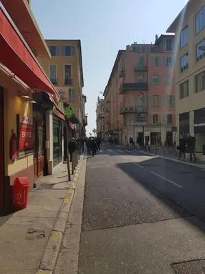 an empty city street with people walking on the sidewalk at Studette en plein cœur du Vieux Nice in Nice