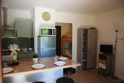 a kitchen with a table and a clock on the wall at Les Palmiers à 700m de la mer in Nice