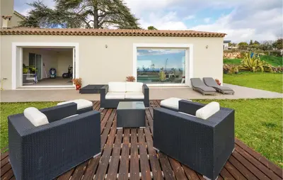 a patio with wicker furniture on a wooden deck at Awesome Home In La Gaude With Kitchen in La Gaude