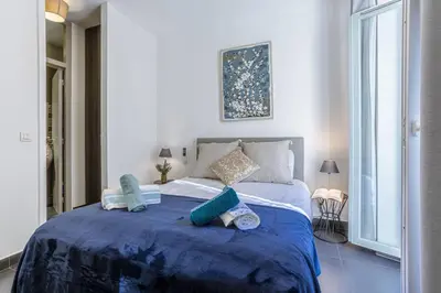 a bedroom with a large bed with blue sheets and pillows at MY CASA - PARADIS - Carré d Or 1 room - Balcony Sea View in Nice
