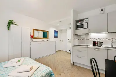 a kitchen with white cabinets and a table in it at Les Oranges Five Stars HolidayHouse in Nice
