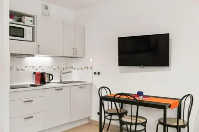 a kitchen with white cabinets and a table with chairs at Les Oranges Five Stars HolidayHouse in Nice